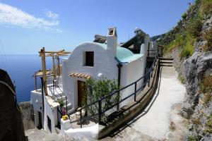 a house on a cliff next to the ocean at La Casa Del Melograno in Furore