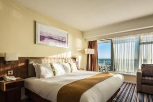 a hotel room with a large bed and a window at Holiday Inn Brighton Seafront by IHG in Brighton & Hove