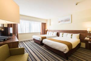 a hotel room with two beds and a television at Holiday Inn Brighton Seafront by IHG in Brighton & Hove