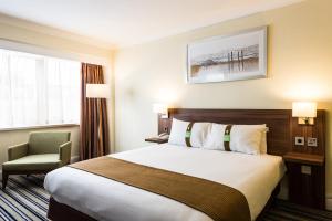 a hotel room with a bed and a chair at Holiday Inn Brighton Seafront by IHG in Brighton & Hove