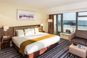 a hotel room with a large bed and a balcony at Holiday Inn Brighton Seafront by IHG in Brighton & Hove +37 photos
