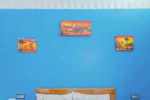 a row of framed paintings on a blue wall at The Rina Hostel in Agadir
