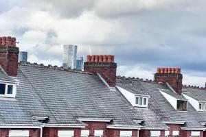 une rangée de toits avec des cheminées en briques et un gratte-ciel dans l'établissement Studio Sleeps3- CloseTo OldTrafford - WhP- o2, à Manchester