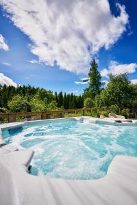 a large swimming pool with blue water at Luxury Glenardle Lodge with Hot Tub and Forest Views in Bridge of Cally
