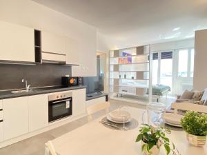 a kitchen and living room with white cabinets and a table at Suite Emilia 6 in Bologna