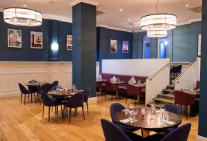 a restaurant with tables and chairs and a staircase at Thistle London Holborn in London