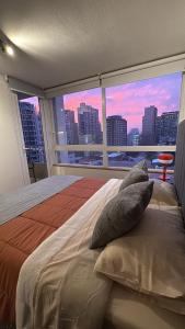 a bedroom with a large window with a view of a city at Departamento en Centro Histórico de Santiago in Santiago