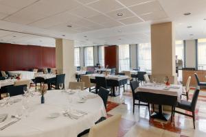 a dining room with white tables and chairs and windows at Hotel Pedro I de Aragón 4 Sup in Huesca