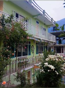 a yellow house with a balcony and flowers at Buddies Stay Café Community in Manāli