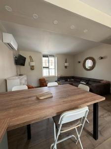 a living room with a wooden table and white chairs at La tanière des ours in Chaumont-sur-Tharonne