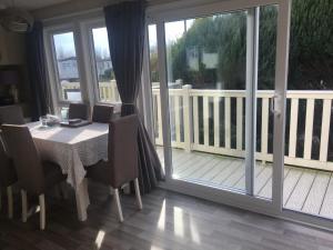 a dining room with a table and chairs and a balcony at 3 bed family static caravan in Selsey