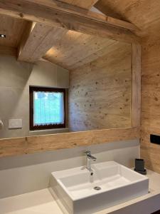 a bathroom with a white sink and a mirror at Sappada Family Apartments in Sappada