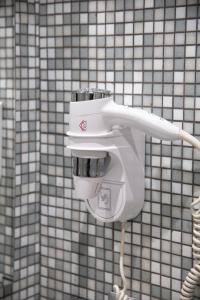 a white hair dryer on the wall of a bathroom at La Maison de Monet in Brindisi
