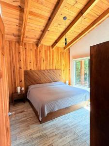 a bedroom with a bed in a room with wooden walls at Nostra Natura Chalets in Mazamitla +38 photos