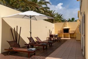 eine Terrasse mit Stühlen, Sonnenschirm und Tisch in der Unterkunft Moradia Felicidade Rocha PXO by An Island Apart in Porto Santo