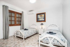 a white bedroom with two beds and a window at Casa Sussa in Tías +17 photos
