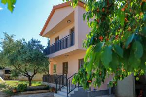 a house with a balcony and a tree at Apartment Ante in Bibinje