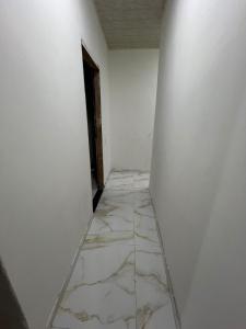 an empty corridor with white walls and marble floors at Acomodação COP30 in Ananindeua