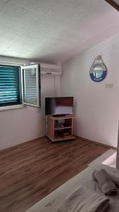 a living room with a flat screen tv and a wooden floor at Old Town Primošten in Primošten