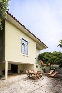 a patio with chairs and a table in front of a house at Vila Mar Beach House in Arcozelo