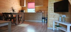 een woonkamer met een keuken en een tv aan de muur bij Domki Milena in Mieroszyno