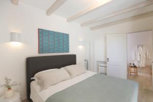 a white bedroom with a bed and a blue picture at Masseria Borgo Sentinella in Torre dell'Orso