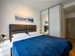 a bedroom with a large bed with a blue blanket at Apartman Adriatico 10 in Bar, Susanj