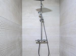 a shower in a bathroom with white tiles at Apartman Adriatico 10 in Šušanj +29 photos