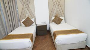 two beds in a room with white sheets and brown pillows at شقق رايف الشرقية in Dammam +10 photos