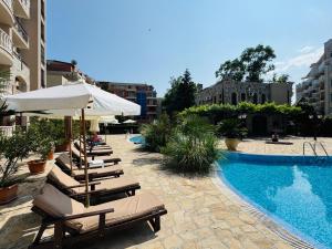 a group of chairs and umbrellas next to a pool at KALIA C9 One Bedroom Apartment in Sunny Beach