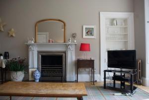 a living room with a fireplace and a tv at Victorian Apartment with car parking in driveway, Murrayfield in Edinburgh