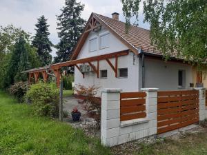 a small white house with a wooden fence at Nefelejcs-el vendeghaz in Balatonmáriafürdő