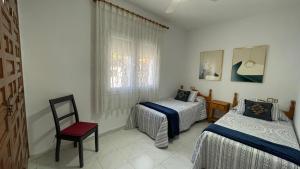 a room with two beds and a chair and a window at MEDDAYS Villa MARINA in Miami Platja