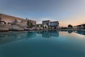 a swimming pool with blue water in front of some buildings at Masseria Borgo Sentinella in Torre dell'Orso
