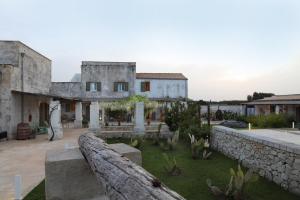 an old house with a stone wall and a yard at Masseria Borgo Sentinella in Torre dell'Orso