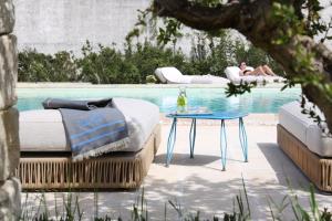 a bed and a table next to a swimming pool at Masseria Borgo Sentinella in Torre dell'Orso