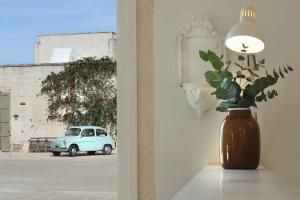 a vase with a plant on a wall with a car at Masseria Borgo Sentinella in Torre dell'Orso