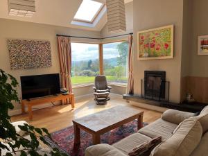 a living room with a couch and a tv and a window at Ballycorrigan Lodge Luxury house for up to 12 guests in Ballina