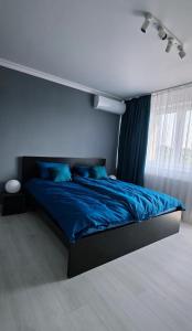 a bedroom with a bed with blue sheets and a window at RVR Apartmanhàz in Sárospatak