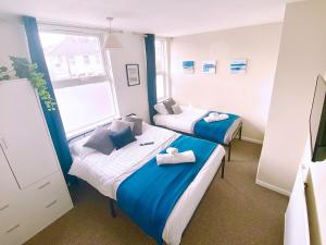 Dos camas en una habitación con azul y blanco. en Clarence Road, Bilston, WV14, en Bilston