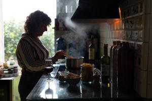 a woman standing in a kitchen with a glass of wine at Hostel du chateau in Saint-Émilion