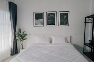 a bedroom with a white bed with three pictures on the wall at SomeNights in Thongsala