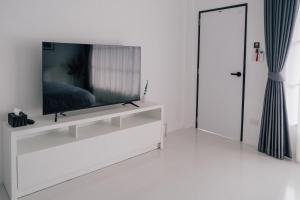 a white living room with a flat screen tv on a white wall at SomeNights in Thong Sala