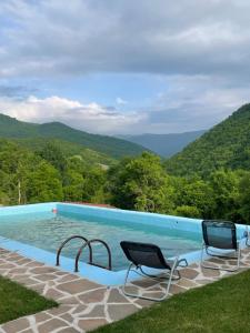a swimming pool with chairs and mountains in the background at Jaćimov Konak in Pirot