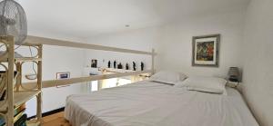 a white bedroom with a bed and a ladder at T1 Pinedda, Studio confort-Vue mer- Calme & soleil in Propriano