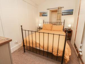 a small bedroom with a bed with orange sheets at Tryfan Cottage in Caernarfon