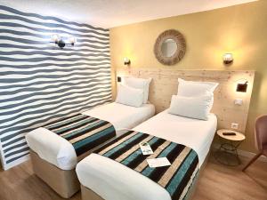 a hotel room with two beds and a striped wall at Sure Hotel by Best Western Biarritz Aeroport in Biarritz