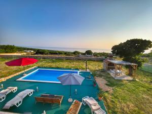 a swimming pool with umbrellas and chairs and a table at Vila Cicovac in Novalja