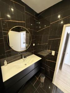 a black tiled bathroom with a sink and a mirror at F3 centre-ville, parking privé in Auxerre
