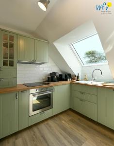 a kitchen with green cabinets and a sink and a window at Haus Christine Ferienwohnung 4 in Langeoog +25 photos